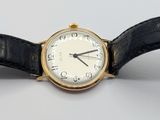 a gold wrist watch with a white face and black leather band