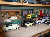 Plusieurs petites voitures sont posées sur une étagère devant un magasin.