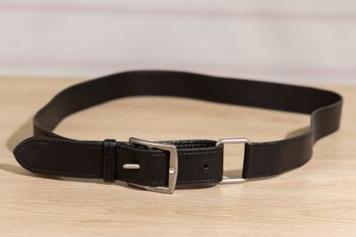 a close up of a black leather belt on a wooden table