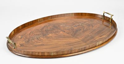 an oval wooden tray with brass handles on a white background
