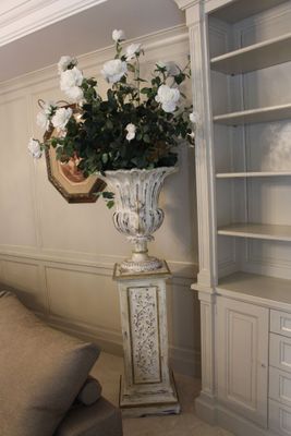 un grand vase rempli de fleurs, posé sur un socle