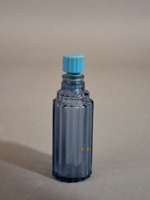 une petite bouteille bleue avec un bouchon bleu posée sur une table