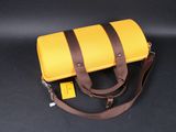 yellow and brown leather bag on black background with brown strap