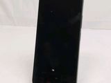 a black cell phone sitting on a stand on a white surface