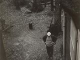 black and white photograph of a woman standing in a yard next to a dog