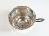 a silver cup with a handle on a white table