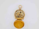 a close up of a pocket watch on a white surface