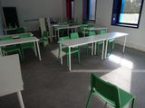 des tables et des chaises dans une salle de classe vide aux fenêtres lumineuses