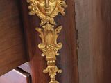 a wooden cabinet with a marble top and a gold face on it
