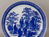 a blue and white plate with a painting of people on it