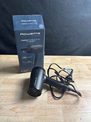 a close up of a black blow dryer sitting on a wooden table