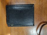 a black wallet sitting on a wooden table next to a charger