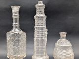 three clear glass bottles sitting next to each other on a table