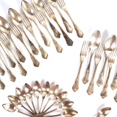de nombreuses cuillères en argent et des cuillères à soupe posées sur une surface blanche