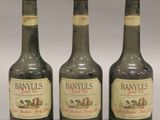 trois bouteilles de brandy sont alignées sur une surface blanche