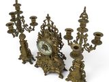 a group of brass candlesticks and a clock on a white background