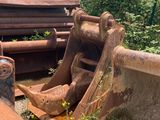 a bulldozer sitting in the grass next to a pile of rusty pipes