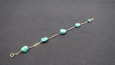 a close up of a bracelet with turquoise beads on a black surface