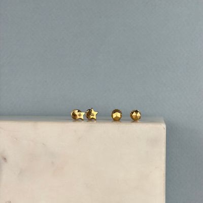 deux boucles d'oreilles en or posées sur un bloc de marbre blanc