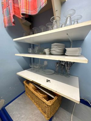 une étagère sur laquelle sont posés de la vaisselle et des verres, dans un coin de la pièce