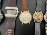 many different types of watches displayed on a black surface