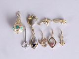 cinq paires de boucles d'oreilles et une broche posées sur un fond blanc