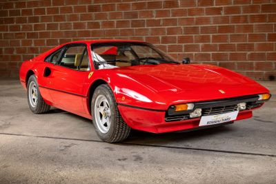 a red sports car parked in front of a brick wall