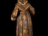 wooden statue of a woman in a brown dress and a hat