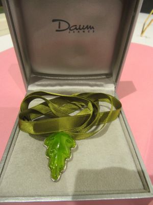 a green leaf in a silver box on a pink table