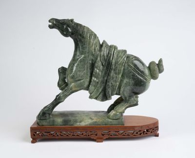 statue d'un cheval au galop posée sur un socle en bois, sur fond blanc