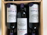 three bottles of red wine in a wooden box on a table