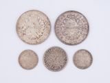 a group of five silver coins on a white surface