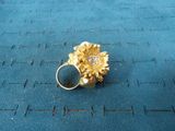 a gold ring with a flower on it on a blue surface