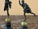 two statues of a man and a woman on top of a ball