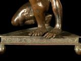 bronze statue of a man kneeling on a platform with his hands on his knees