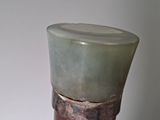 a green vase sitting on top of a wooden stand