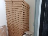 boxes of pizza stacked on top of each other in the corner of a room