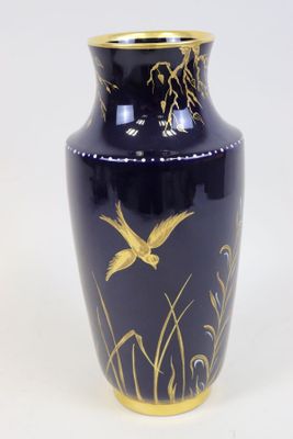 un vase bleu orné de motifs dorés sur un fond blanc