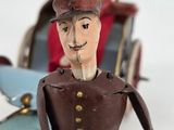 toy figurine of a man riding a toy car with a woman in the background