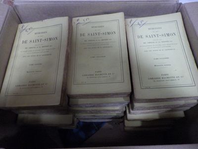 Plusieurs livres sont empilés dans une boîte posée sur une table