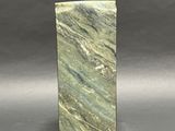 a close up of a green marble block on a gray surface