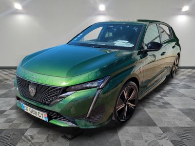 La voiture verte est garée sur un sol à damier, dans une pièce.