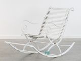 a white rocking chair in a room with a white wall
