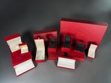 three red boxes with black and white watches in them on a table