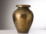 un grand vase en or posé sur une table blanche