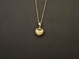 un collier plaqué or avec un pendentif en forme de pomme sur fond noir