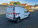 La camionnette est garée sur un parking, avec une échelle à l'arrière.