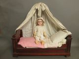 a doll that is sitting on a bed with a canopy over it