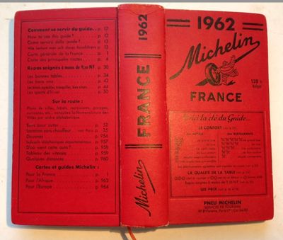 an old book with a red cover sitting on top of a table