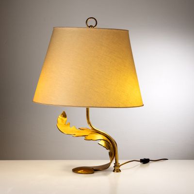 lampe de table en feuille d'or avec un abat-jour beige posée sur une table blanche
